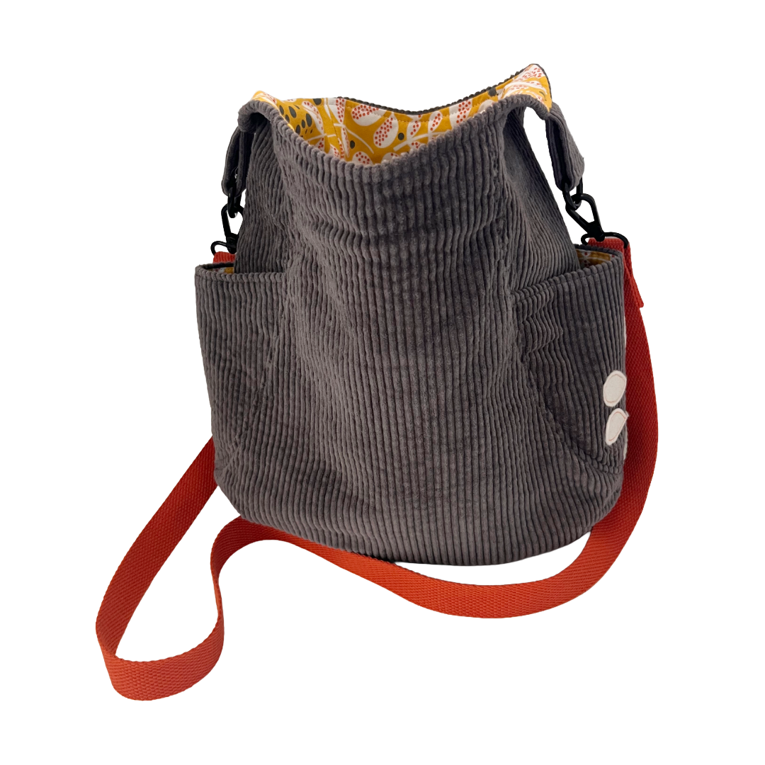 Olive-green corduroy crossbody bag with a bright orange hand-stitched flower appliqué on the flap and a beige adjustable strap.