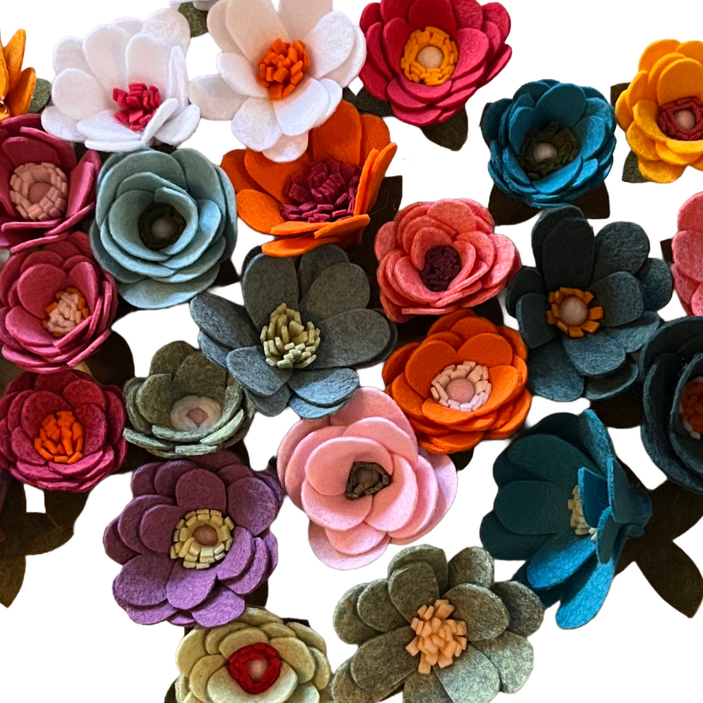 Colorful felt flowers arranged in a pattern on a white background