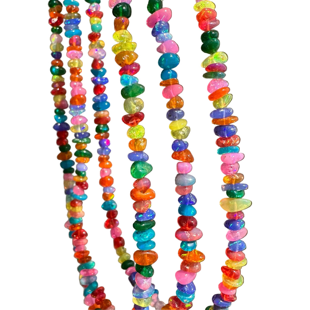 Several strands of colorful tumbled stone beads hanging vertically against a plain taupe-gray background.