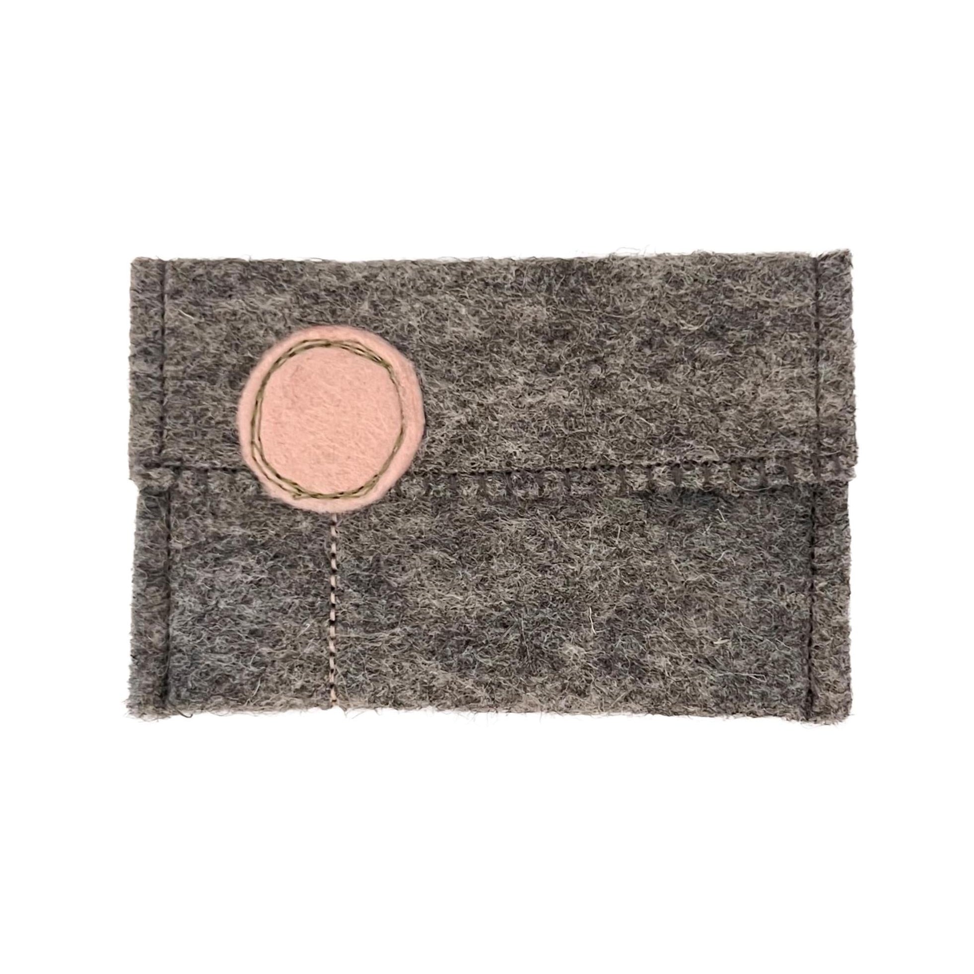 Gray felt pouch with a pink circular patch on a white background
