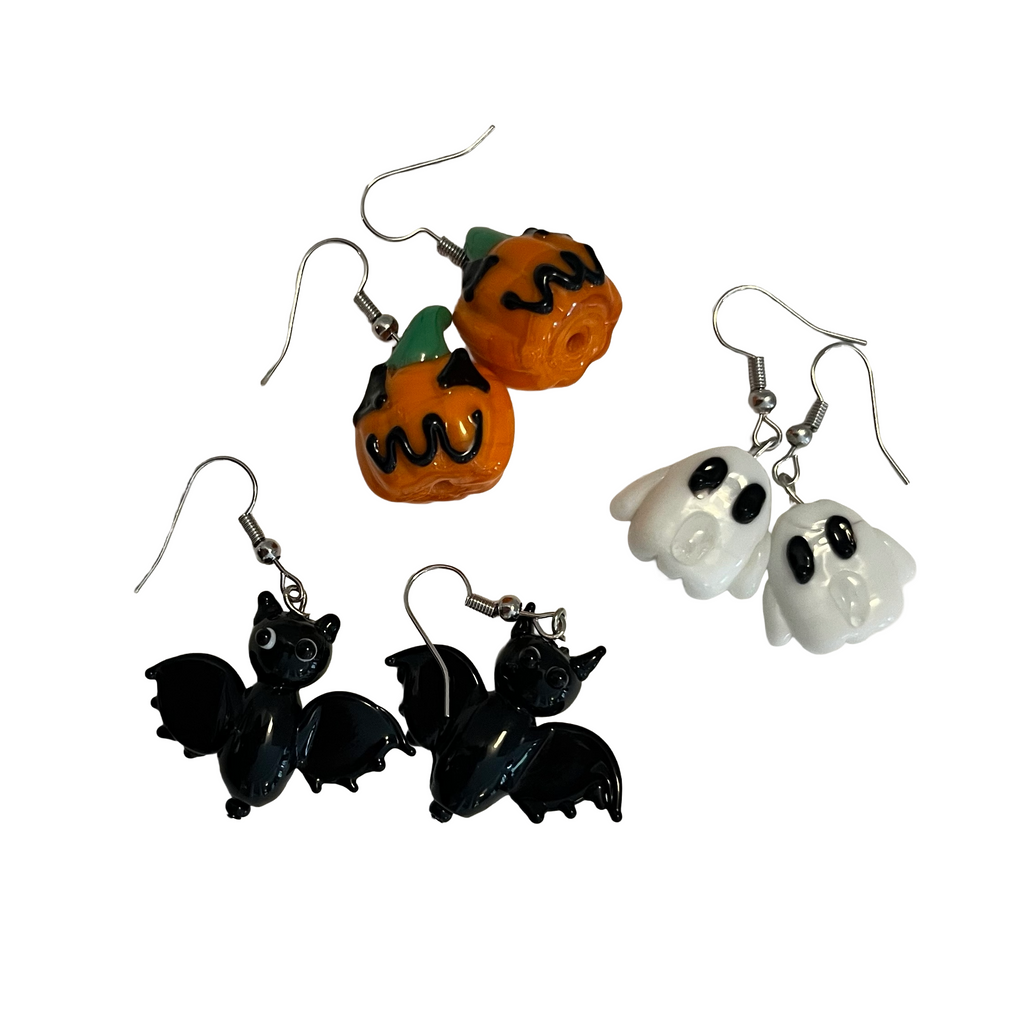 Set of Halloween-themed earrings including pumpkins, ghosts, and bats on a white background.