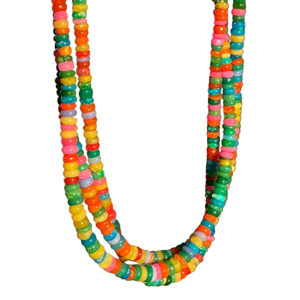 A beaded necklace made of small, round, translucent multicolor beads in shades of green, yellow, orange, pink, and blue, arranged in a U-shape against a solid dark gray background.