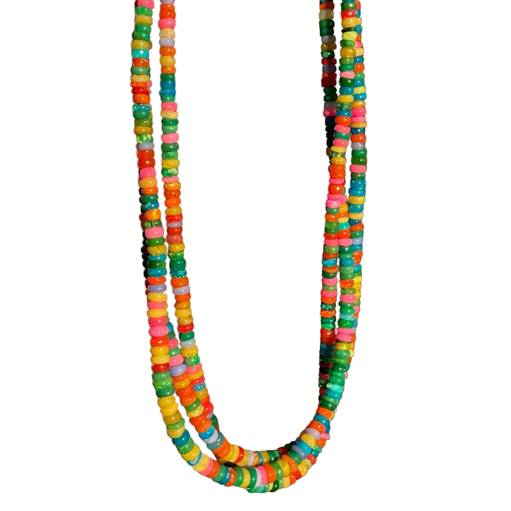Colorful beaded necklace held by a hand against a gray background