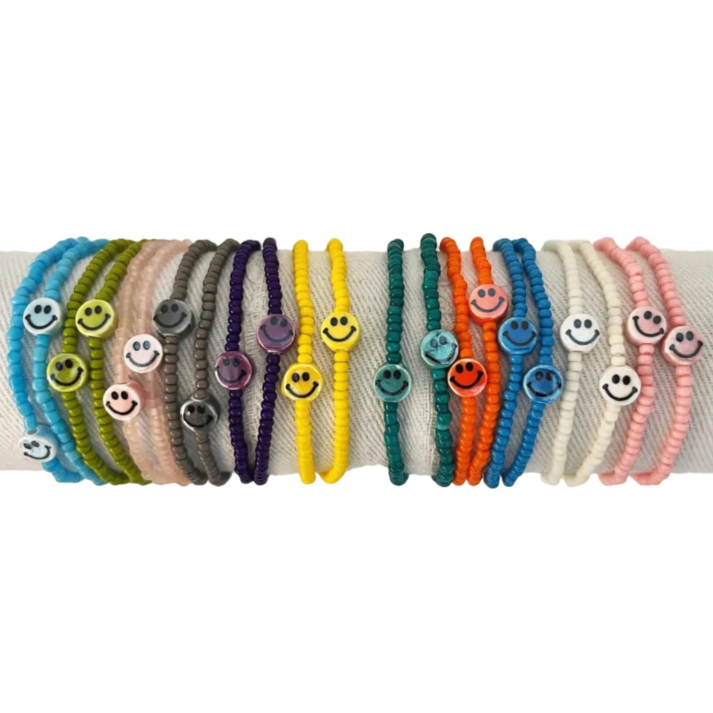 Set of colorful bracelets with smiley face charms on a white background