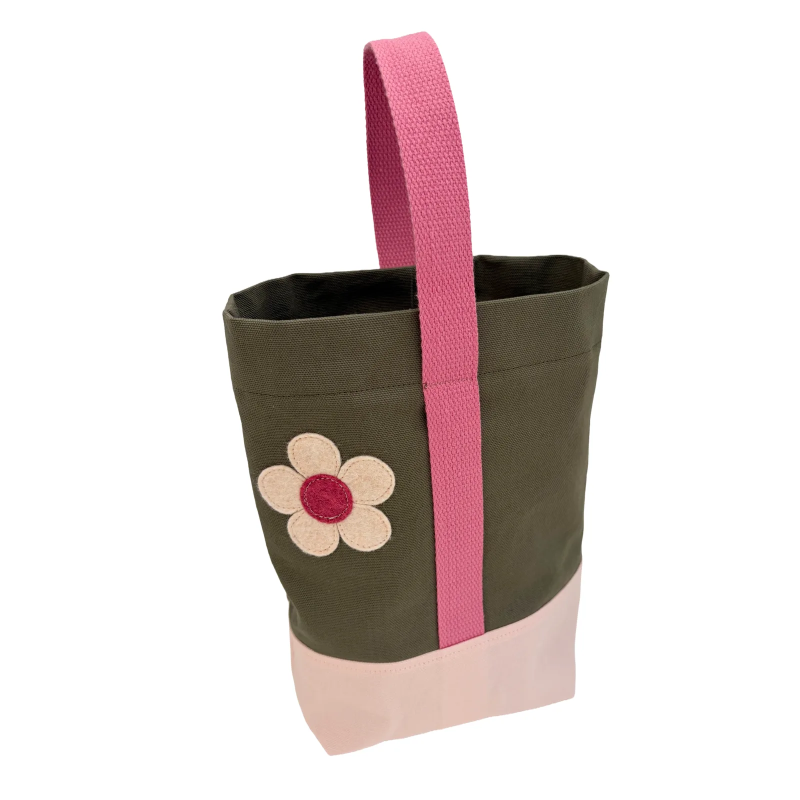 An olive green canvas wine tote bag with a pink woven handle, a light pink bottom panel, and an embroidered flower patch on the front.