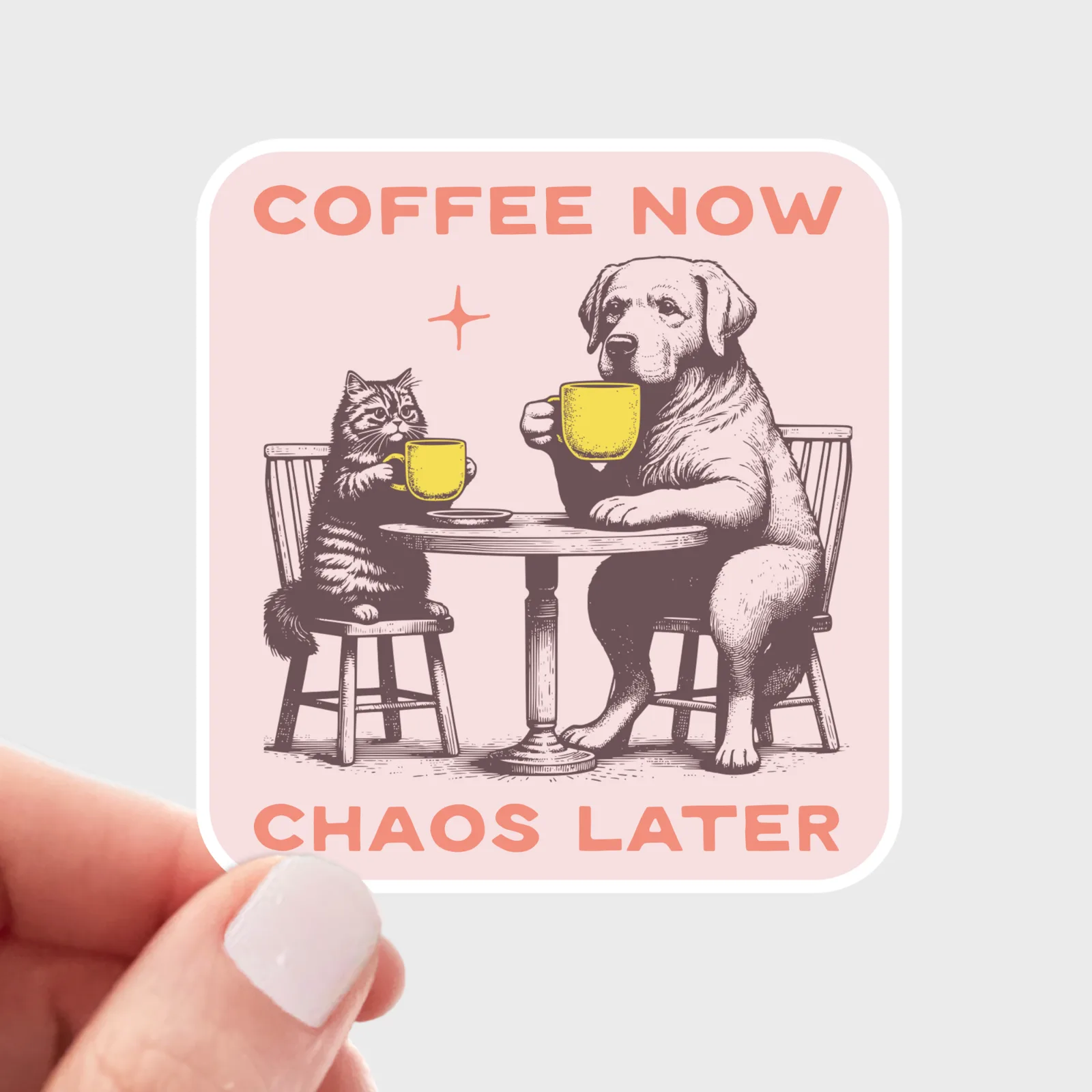 Sticker with a cat and dog at a table with coffee cups and text 'Coffee Now, Chaos Later' held by a hand.