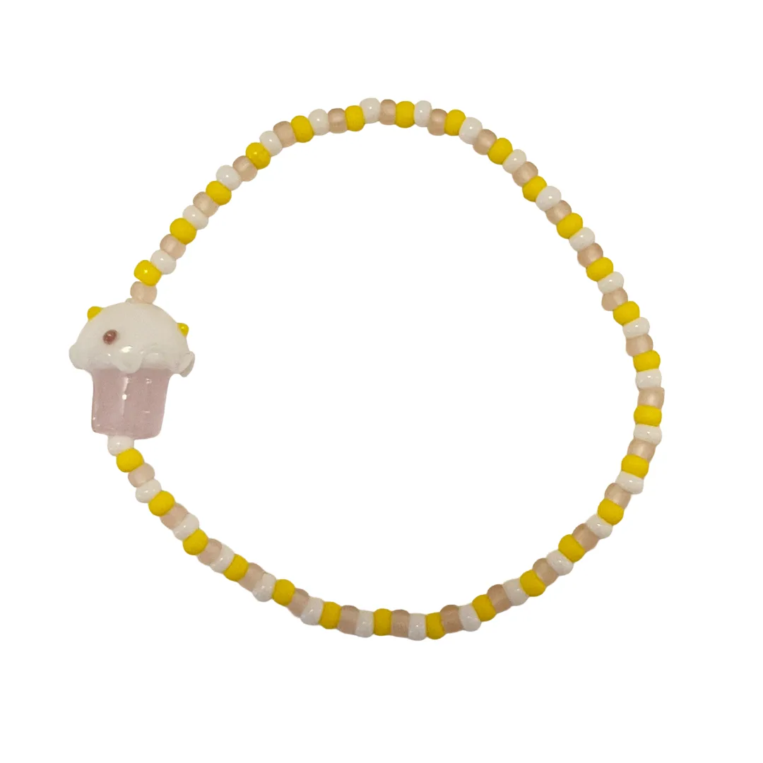Beaded bracelet with a cupcake charm on a white background