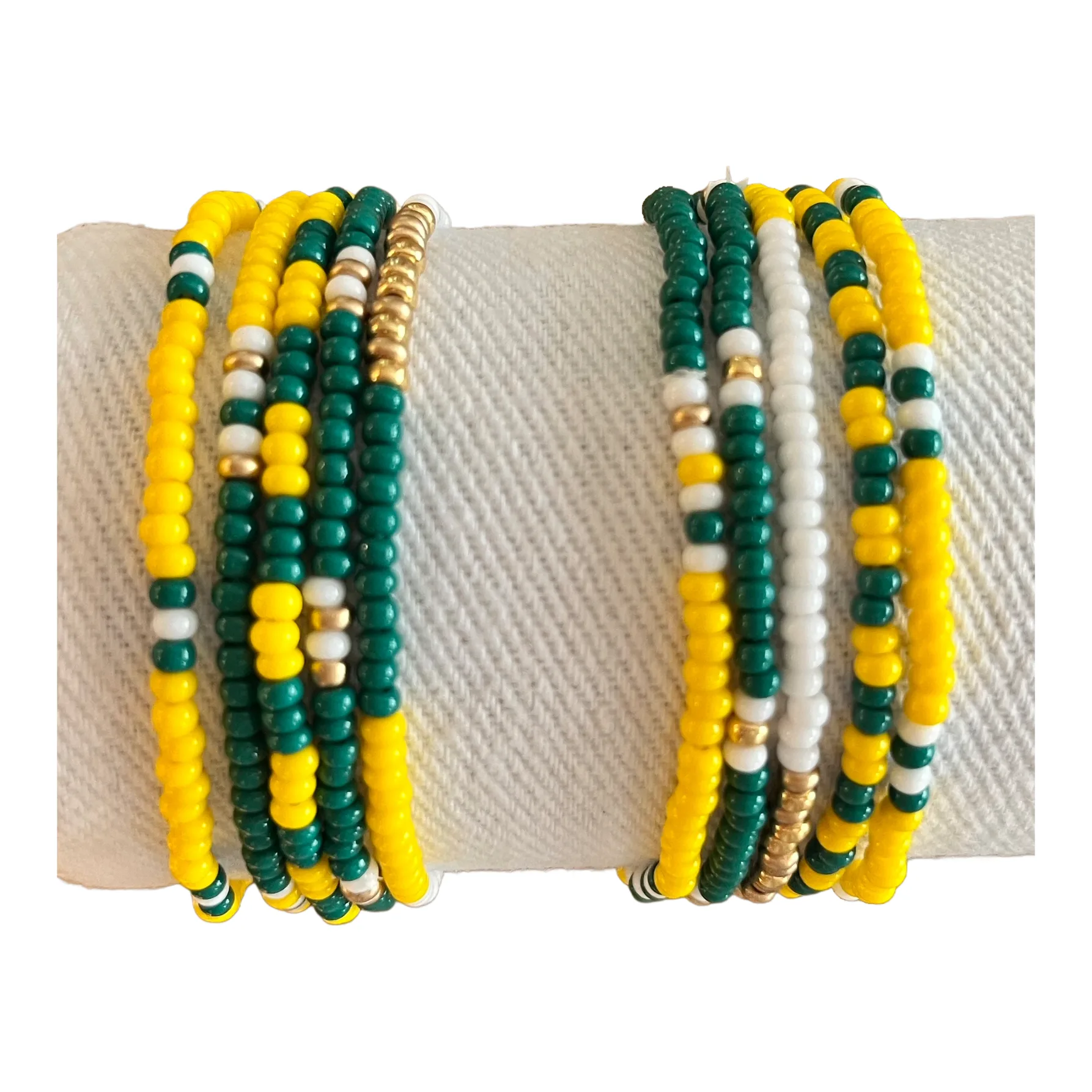 Two stacks of green, yellow, white and gold seed bead bracelets