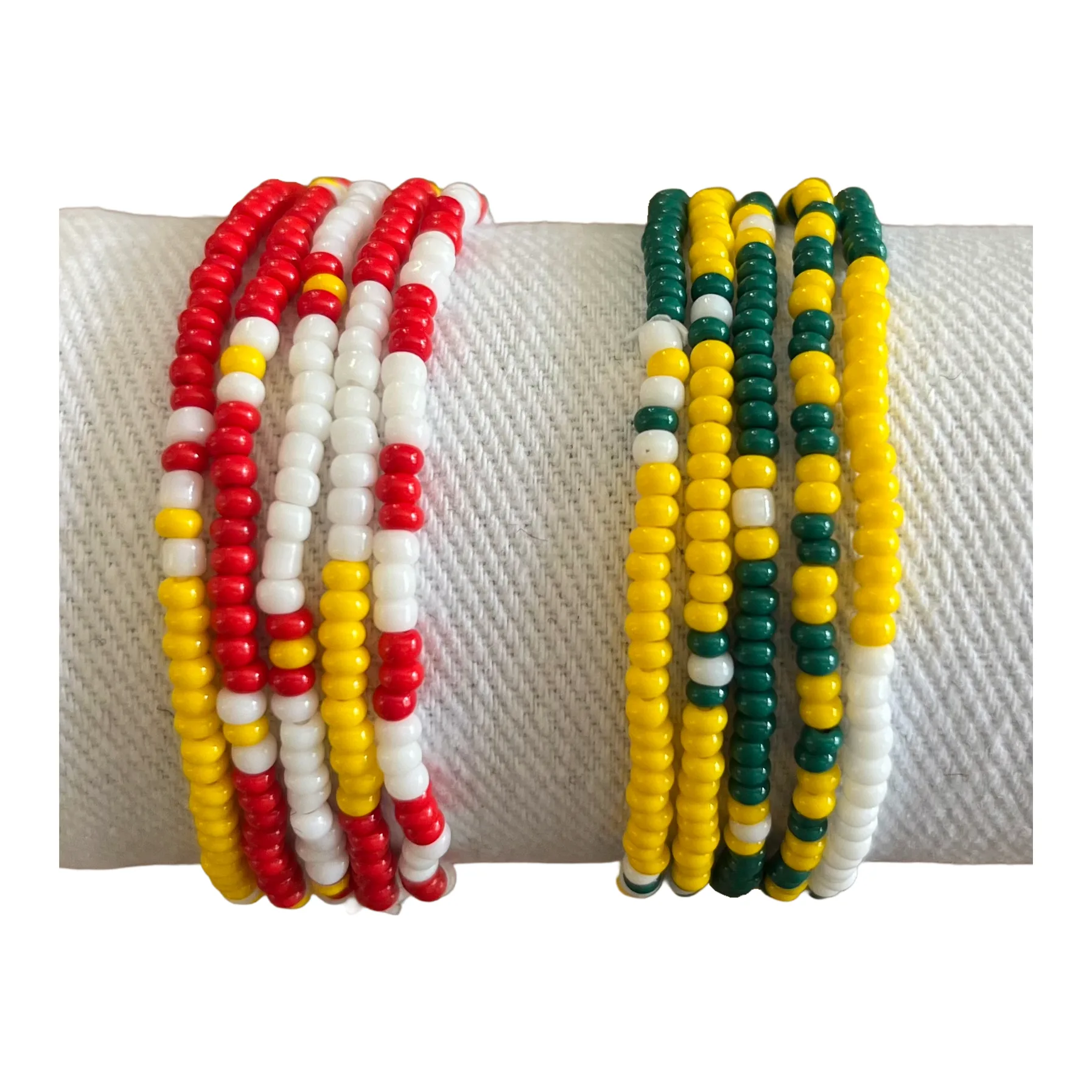 A stack of red, yellow and white bracelets beside a stack of green, yellow and white