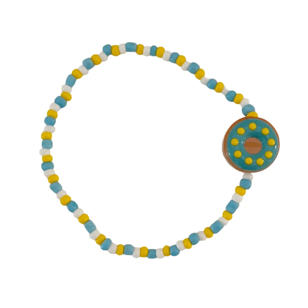 Colorful beaded bracelet with a blue donut bead on a white background