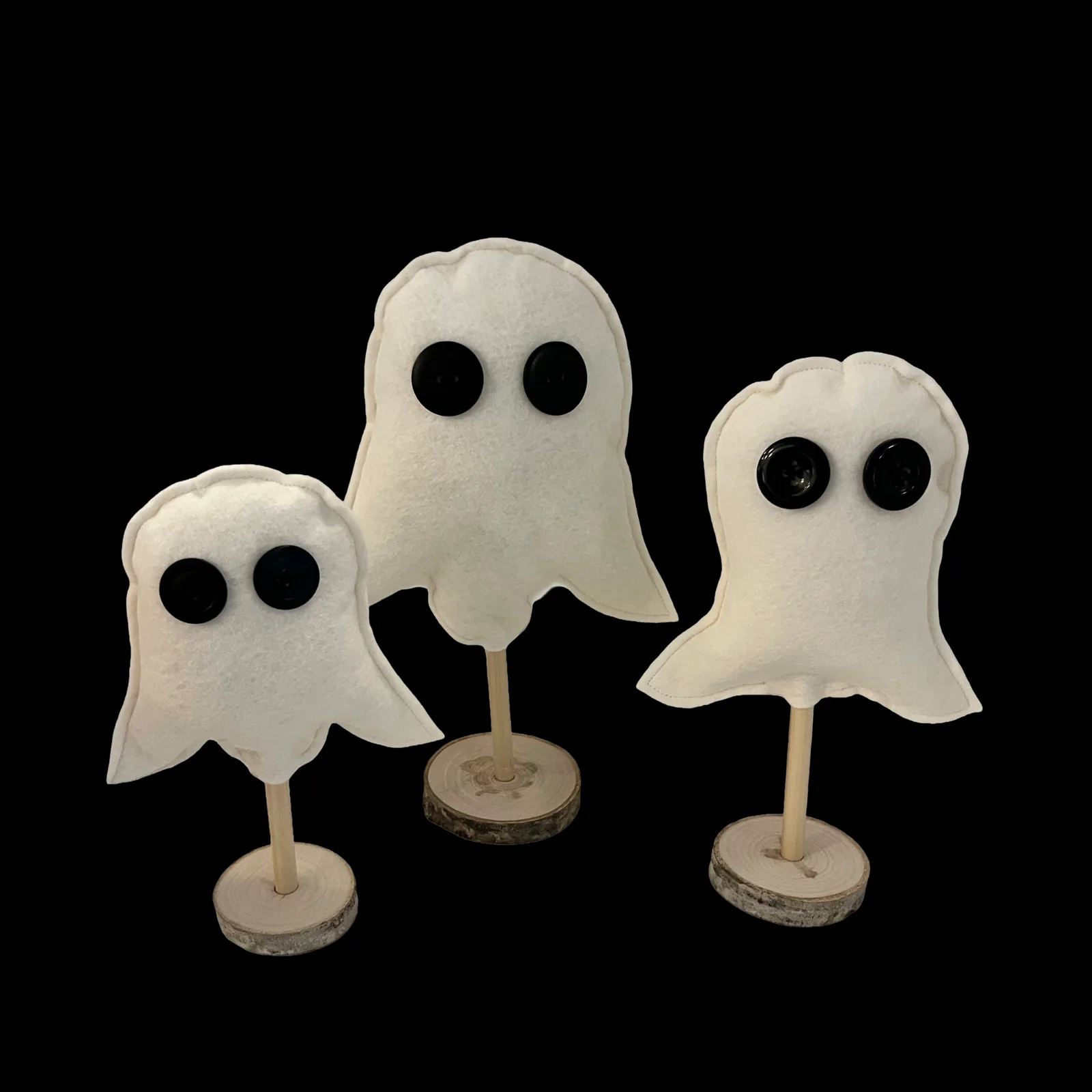 Three ghost-shaped figures on stands against a black background