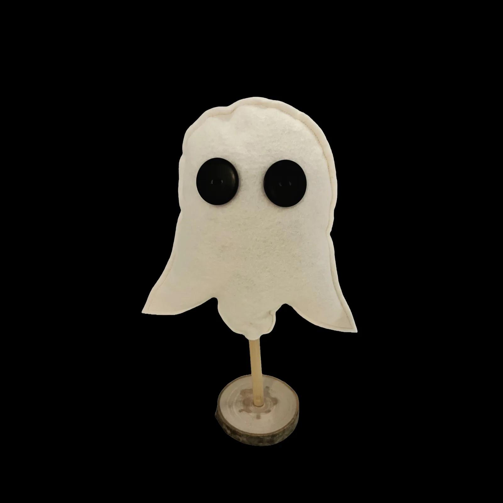 White ghost figure on a stand against a black background