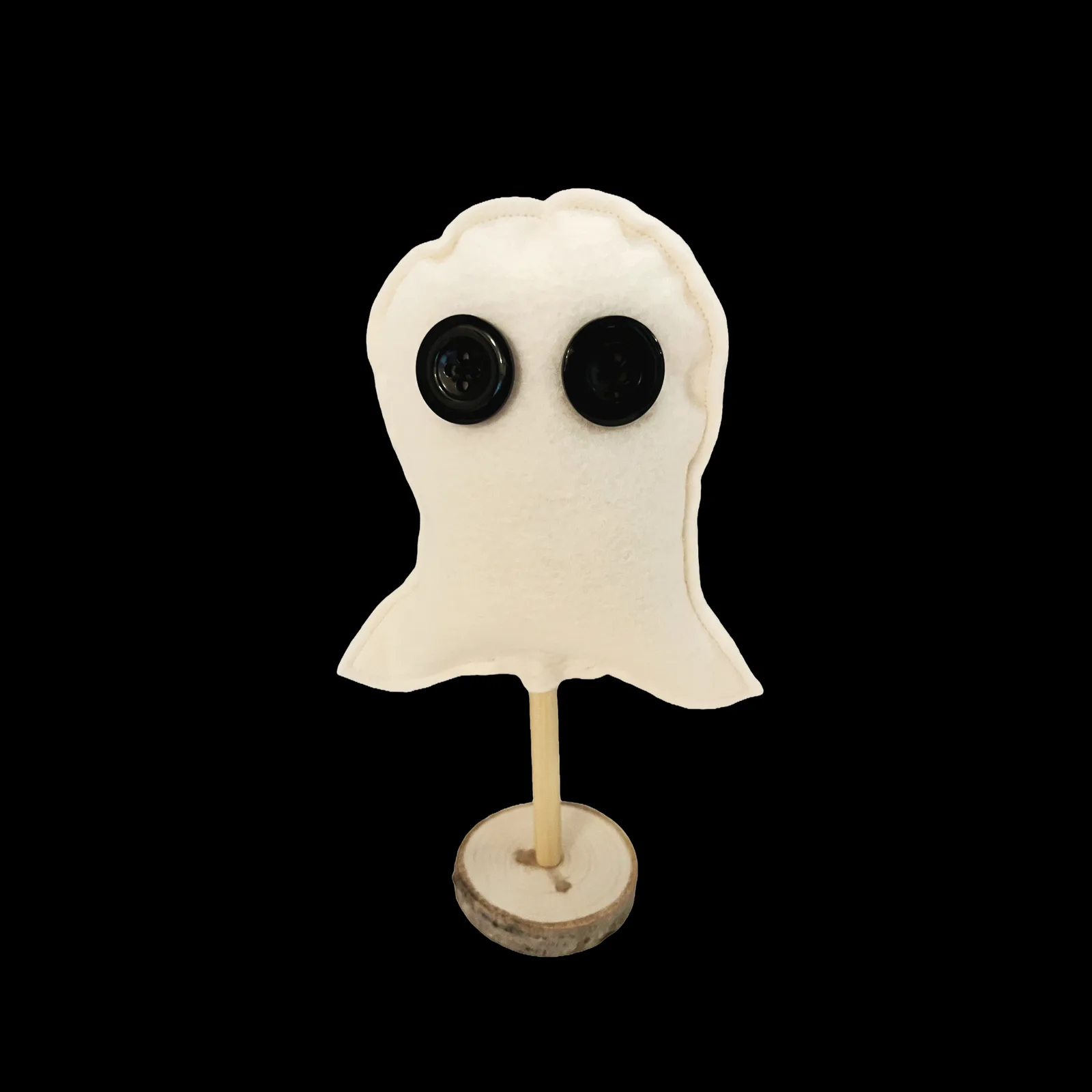 Ghost-shaped object on a stand against a black background