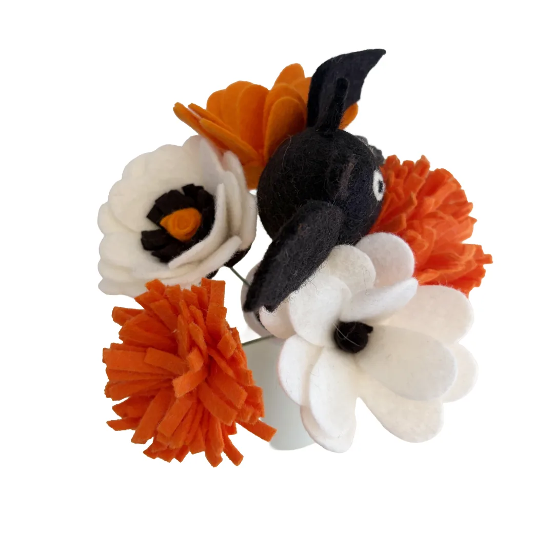 A felt flower and bunny hair accessory on a white background. The accessory features a black felt bunny head with long ears, surrounded by white and orange felt flowers with black centers.