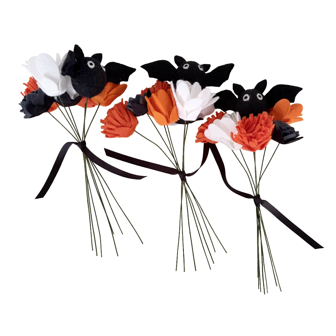 Three small bat-shaped flower bouquets made from black, white, and orange felt flowers with black ribbon stems, shown on a plain white background.