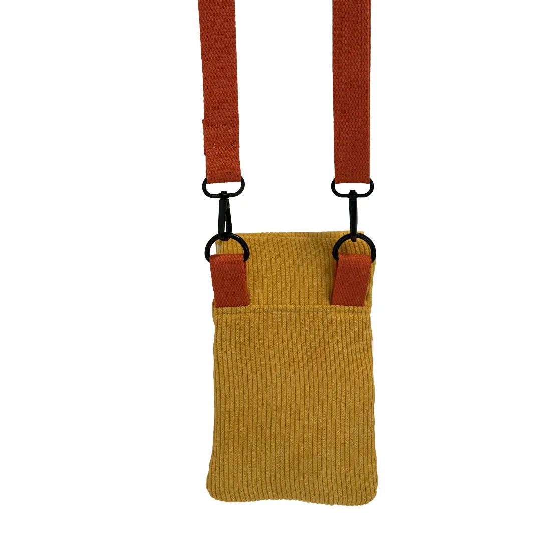 A mustard yellow corduroy crossbody bag with a rust-orange adjustable webbed strap and black metal hardware, shown against a plain white background.