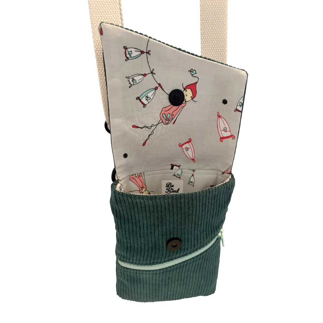 A fabric pouch with a dark teal corduroy lower section and a cream-colored upper flap featuring a whimsical pattern of flying balloons and a red-haired girl. The pouch is shown open against a plain white background.