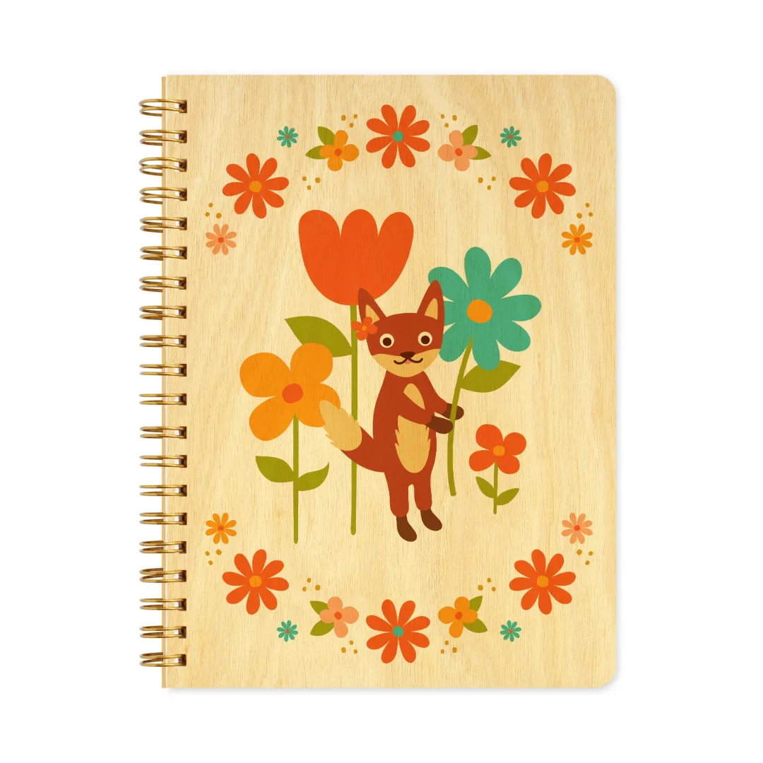 A spiral-bound notebook with a light wood cover featuring a cartoon fox surrounded by colorful flowers, shown on a plain white background.