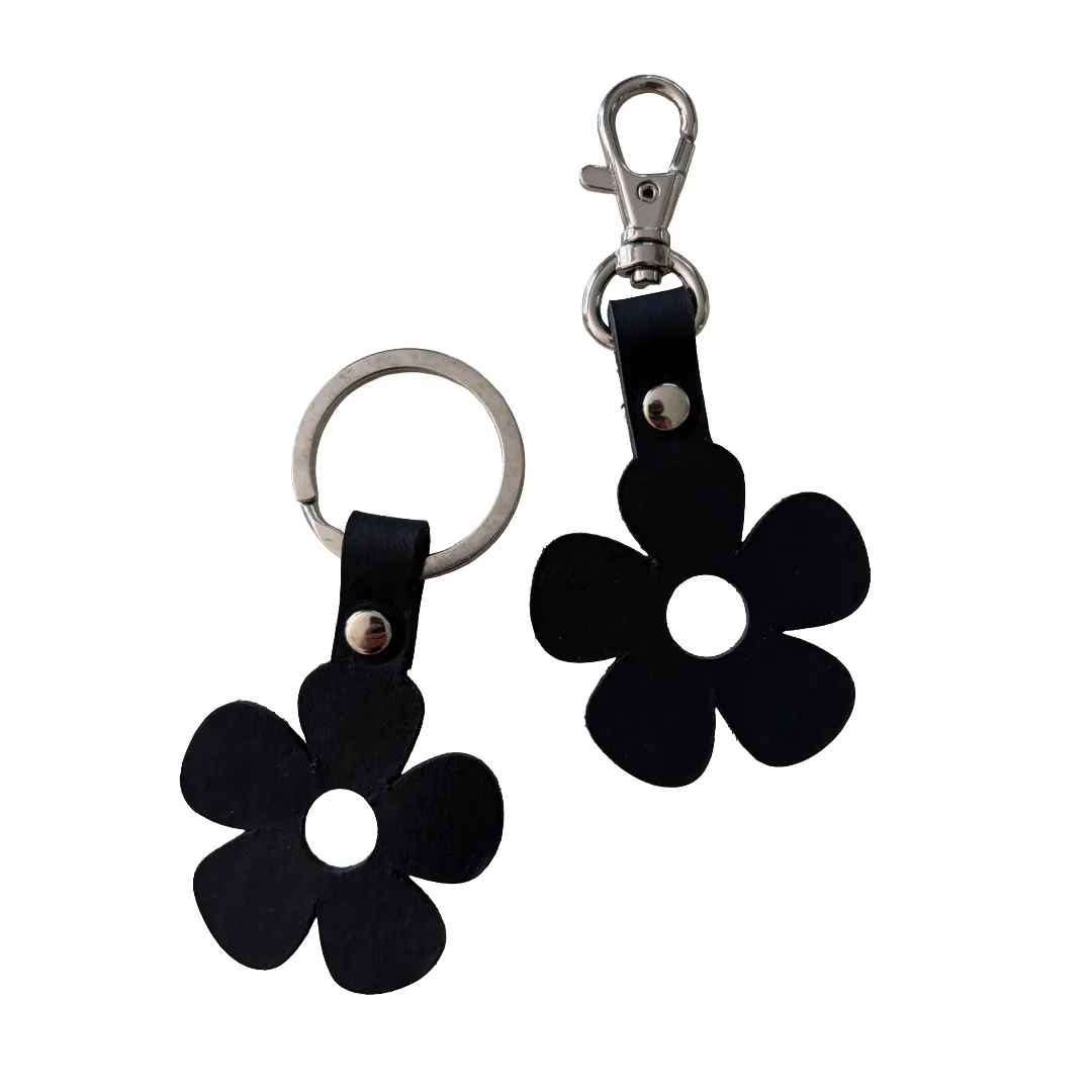 Two black flower-shaped keychains with silver metal key rings and clasp hardware, shown on a plain white background.