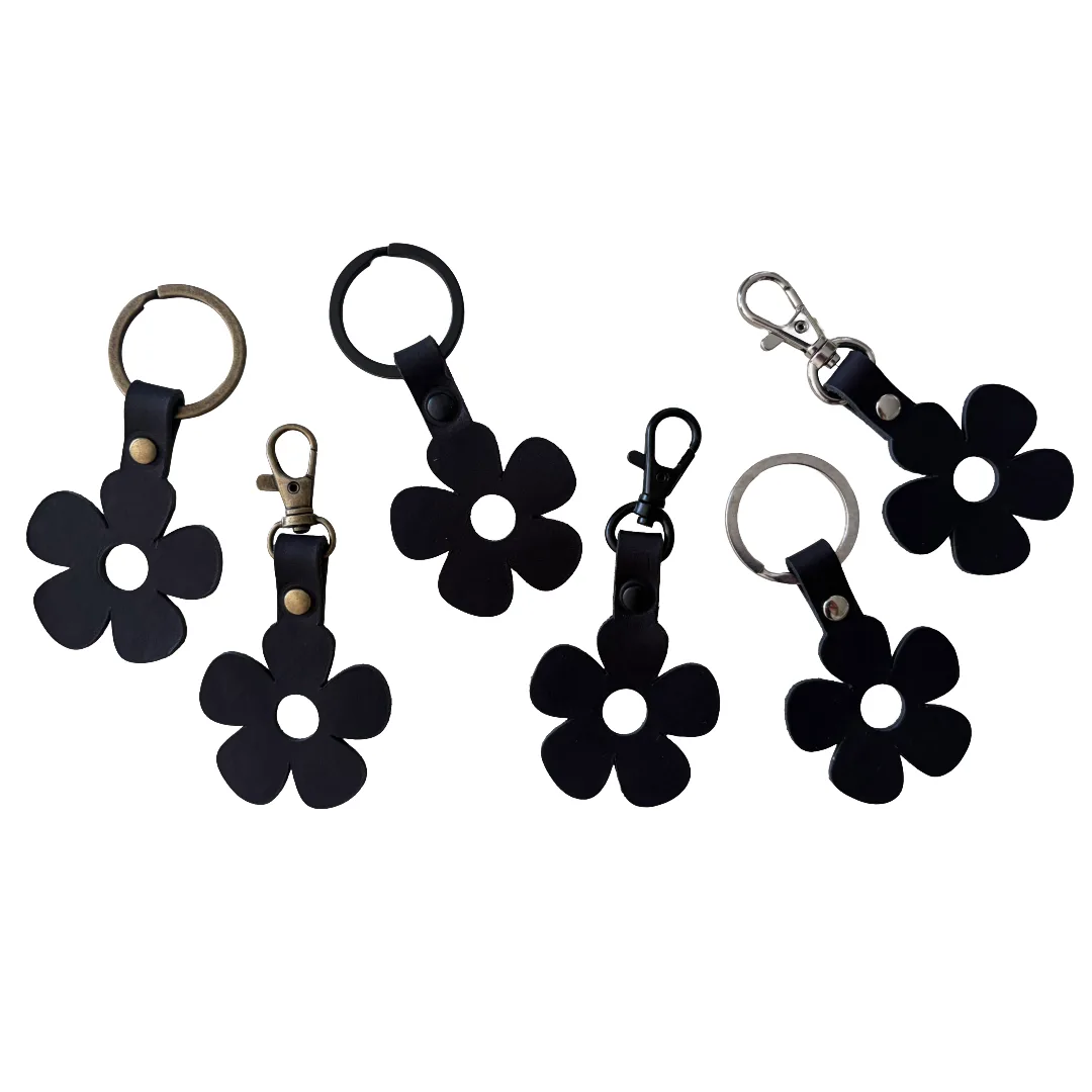 Five black flower-shaped keychains with different metal key rings and clasp hardware, arranged on a plain white background.