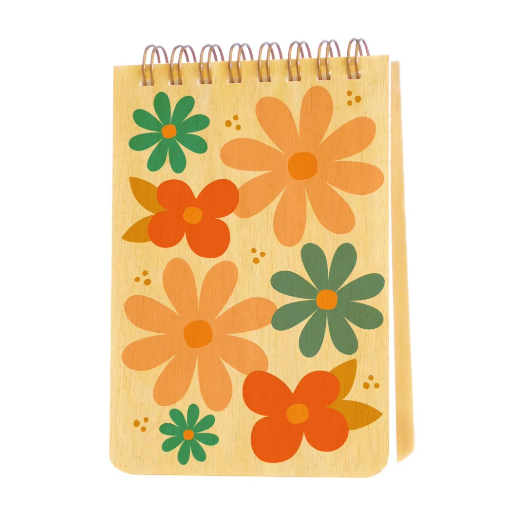 A spiral-bound notebook with a light wood grain cover decorated with retro-style orange and green flowers, shown on a plain white background.