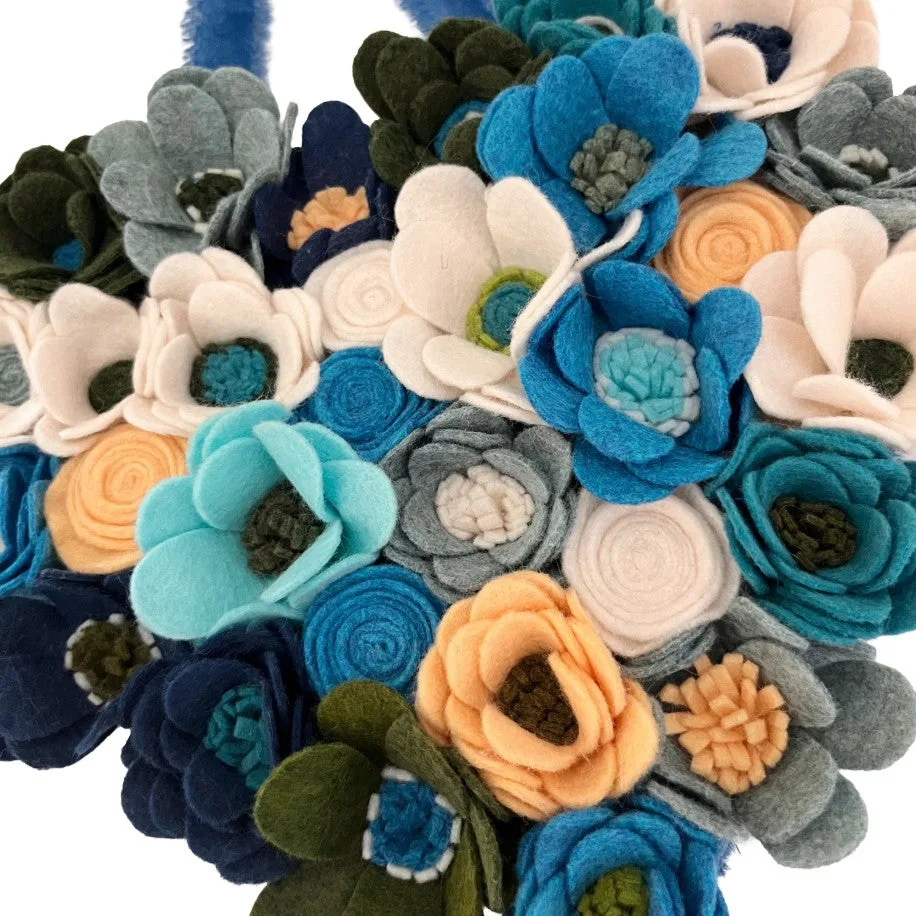 Colorful felt flower heart with blue, cream, and white flowers on a white background