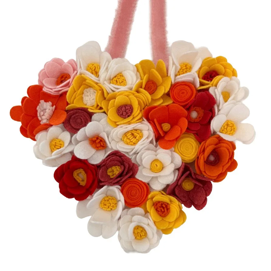 Heart-shaped hanging with colorful felt flowers on a white background