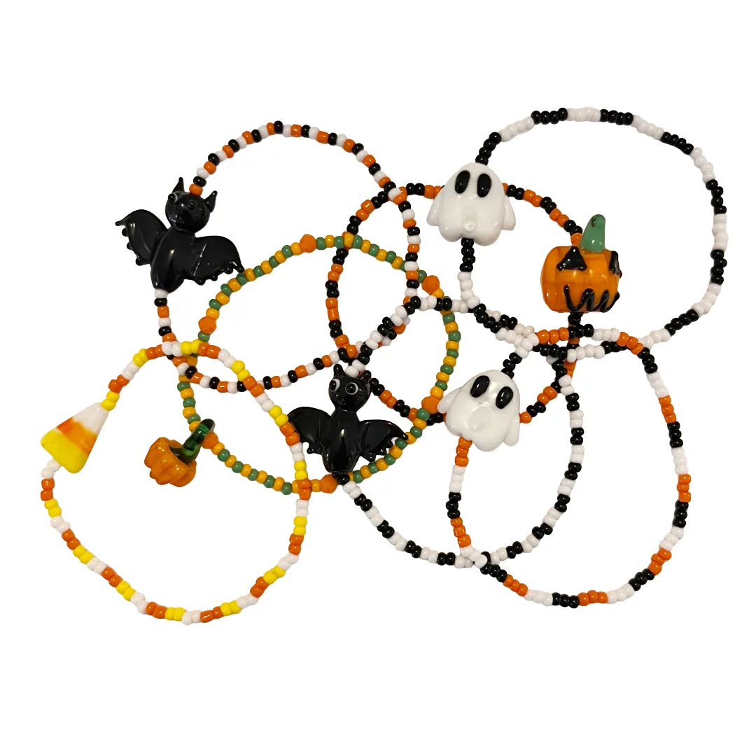 Set of Halloween-themed beaded bracelets with decorative charms on a white background