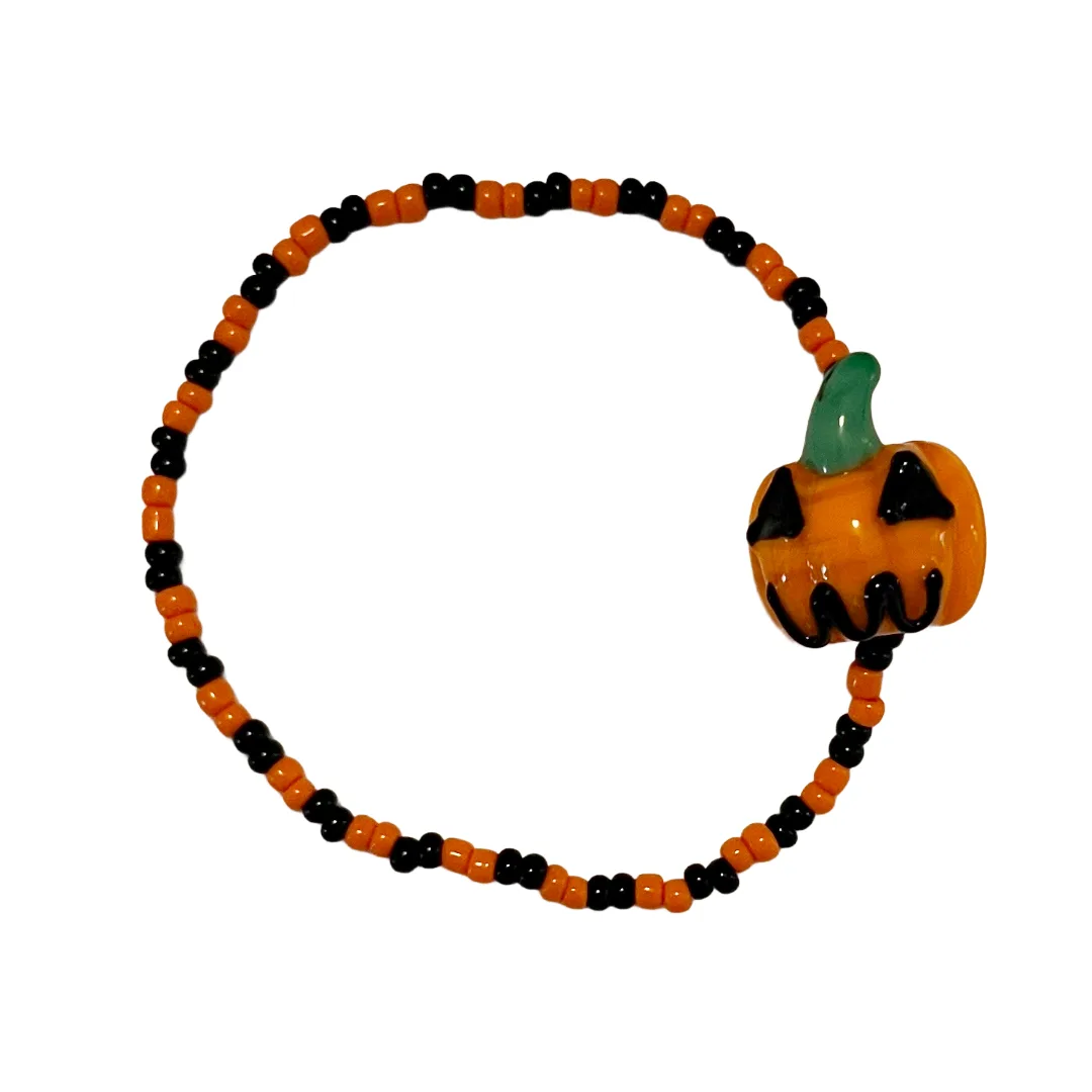 Halloween-themed beaded bracelet with a pumpkin charm on a white background