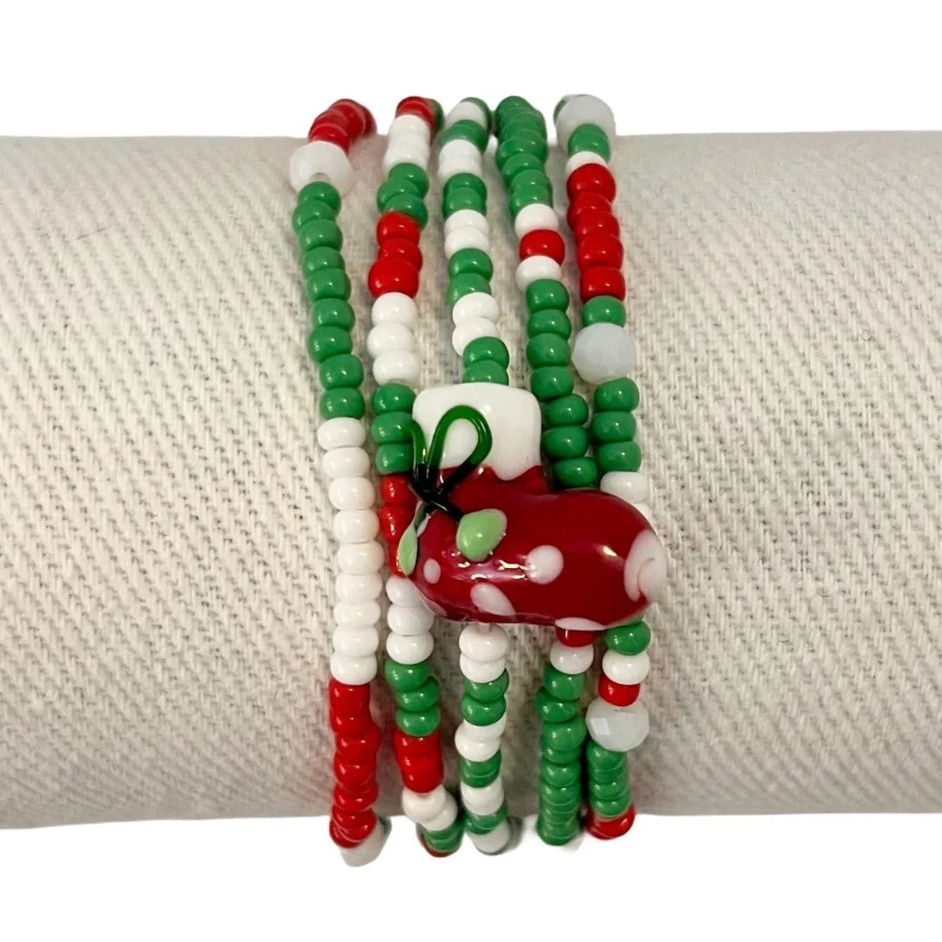 Set of beaded bracelets with a red and green design on a white fabric background