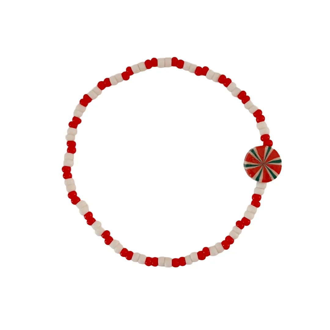 Bracelet with red and white beads and a pinwheel element on a white background