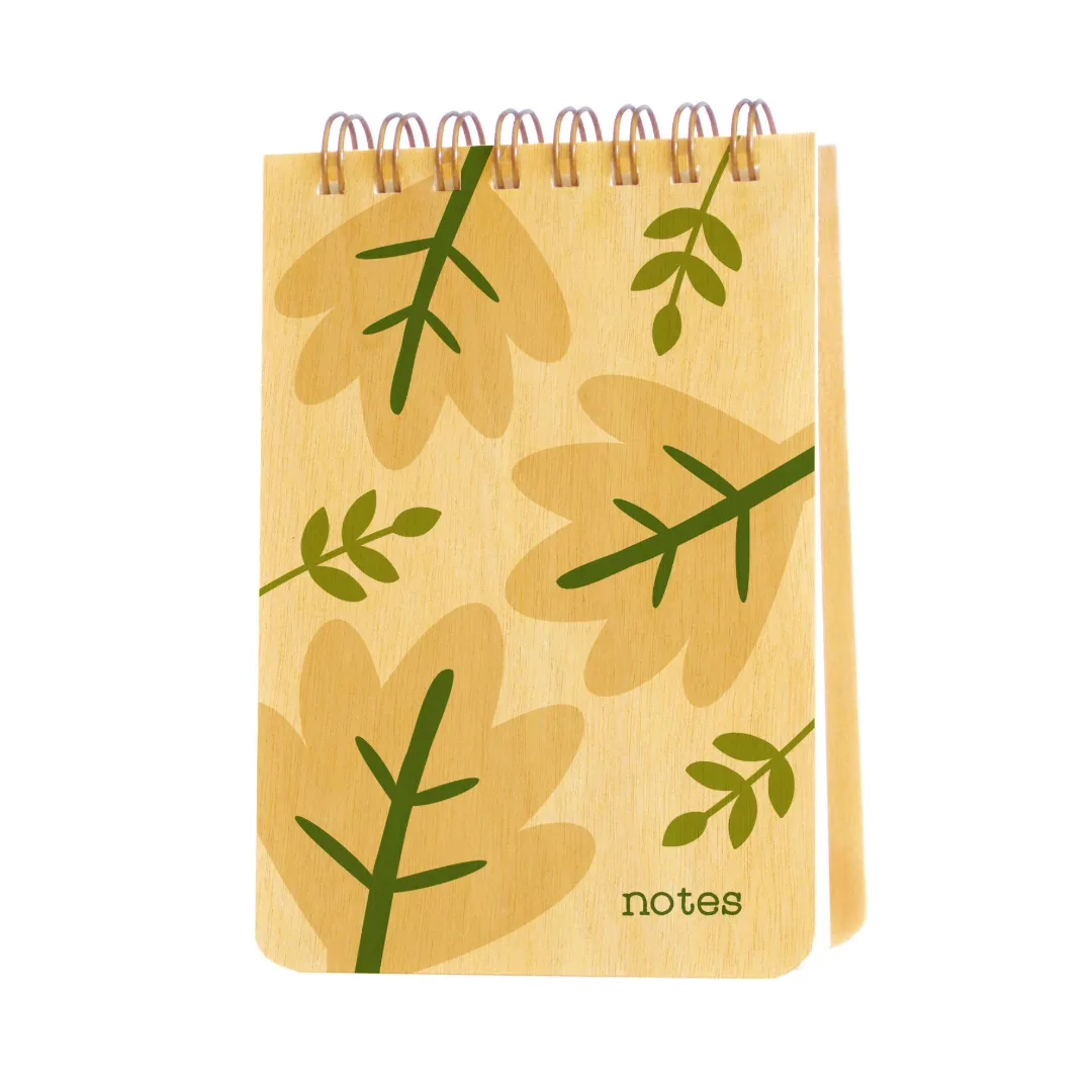 A spiral-bound wooden notes notebook with a light tan wood-grain cover decorated with green leaf patterns and the word 'notes' printed at the bottom, shown on a plain white background.