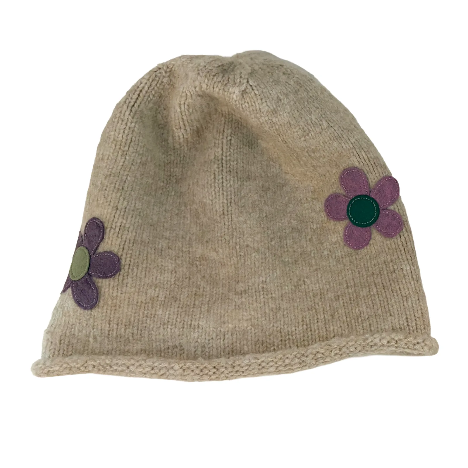 A beige knit beanie hat featuring two purple fabric flowers with green centers on the side, shown against a plain white background.