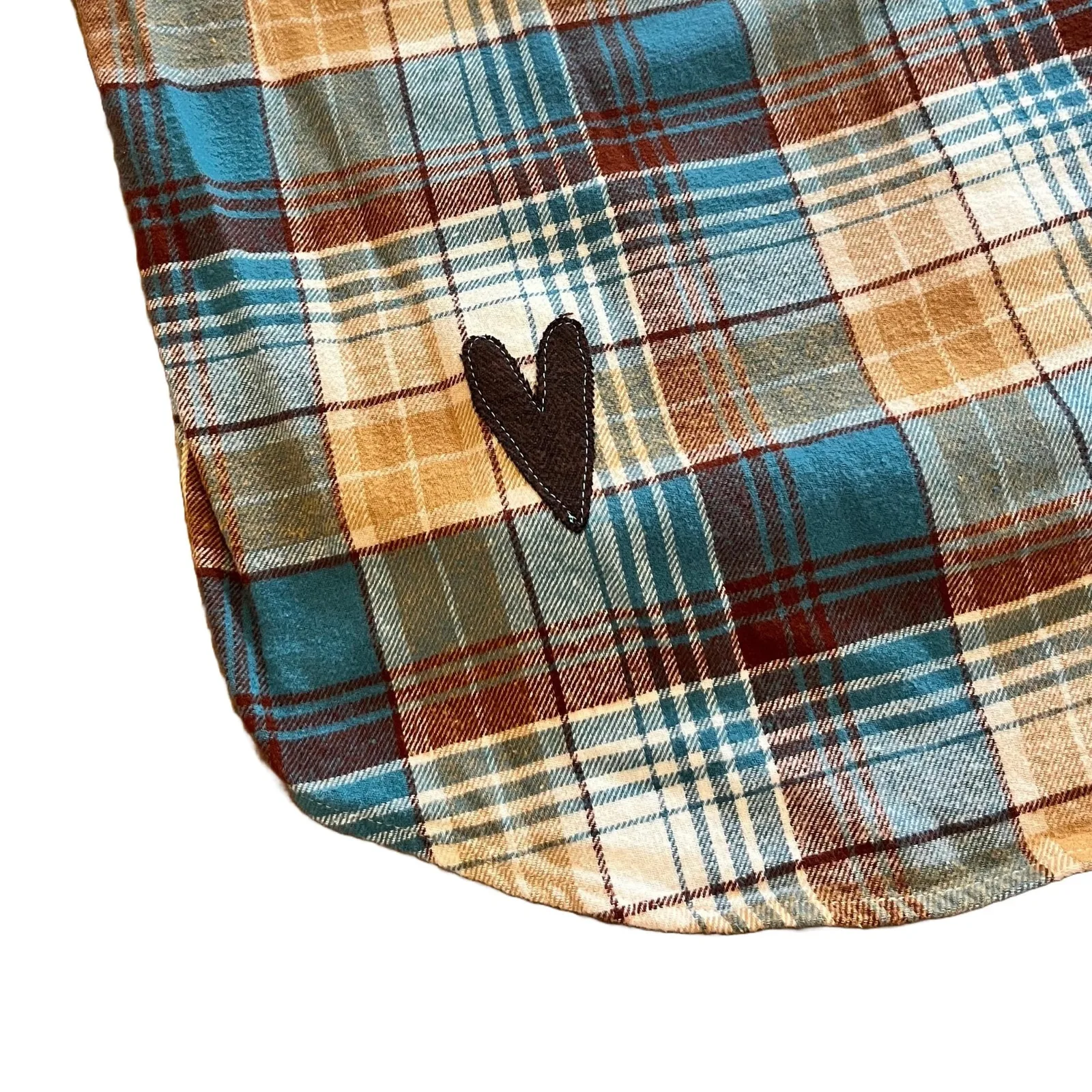 Close-up of a plaid fabric with a heart-shaped patch on a white background
