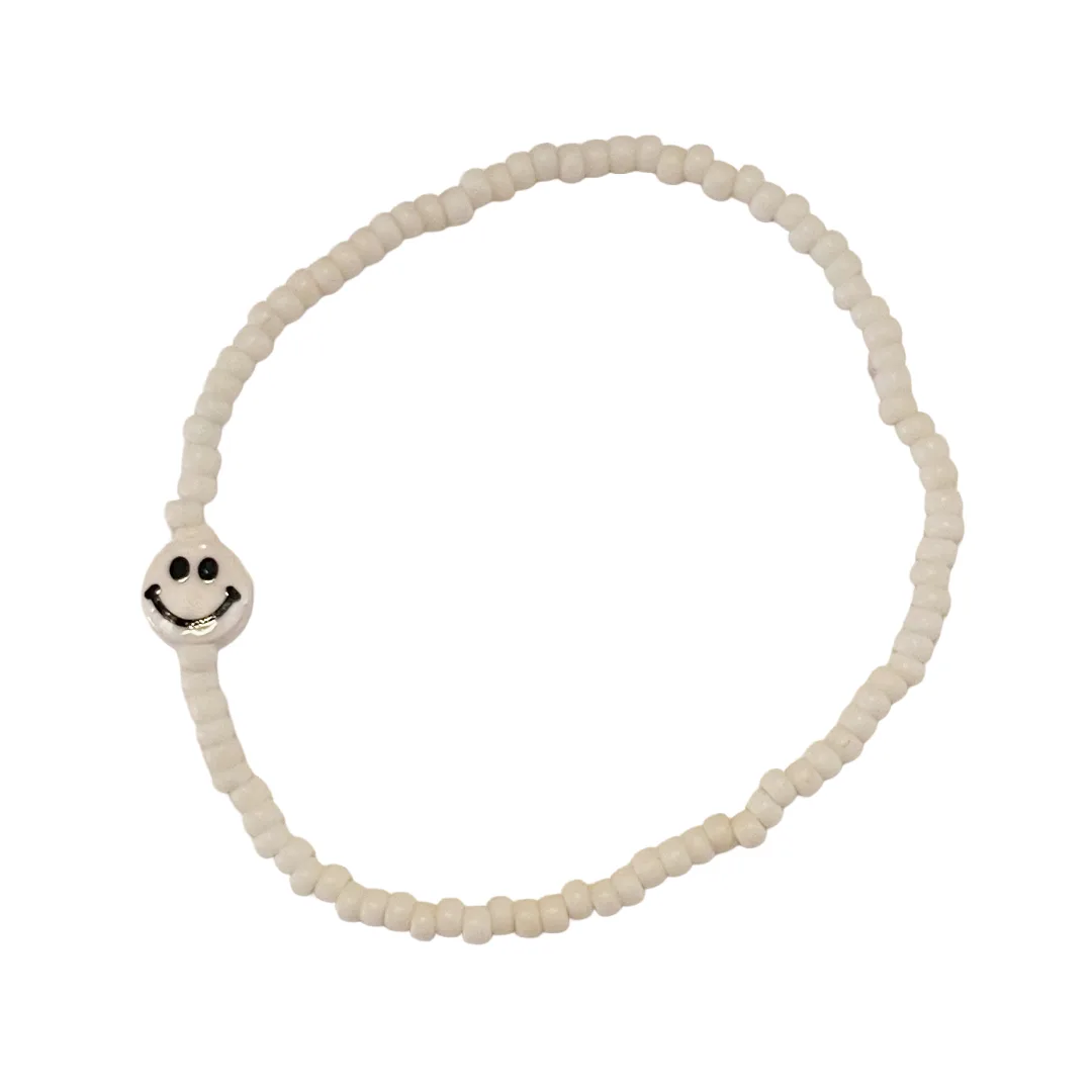 White beaded bracelet with a smiley face charm on a white background