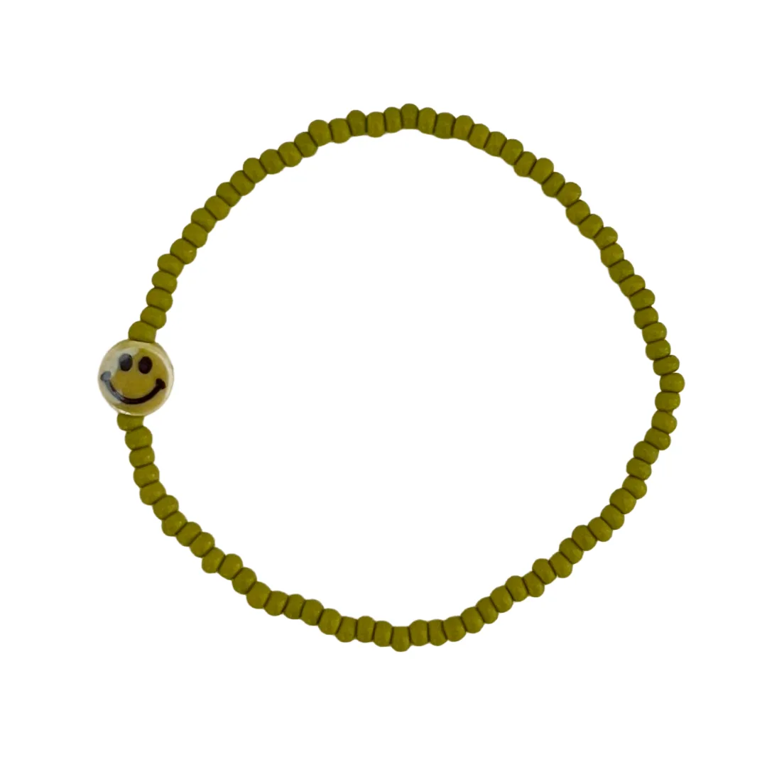Green beaded bracelet with a smiley face charm on a white background