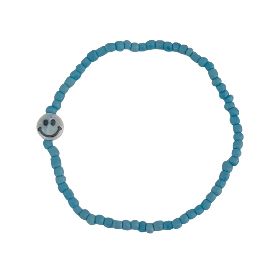 Blue beaded bracelet with a silver smiley face charm on a white background